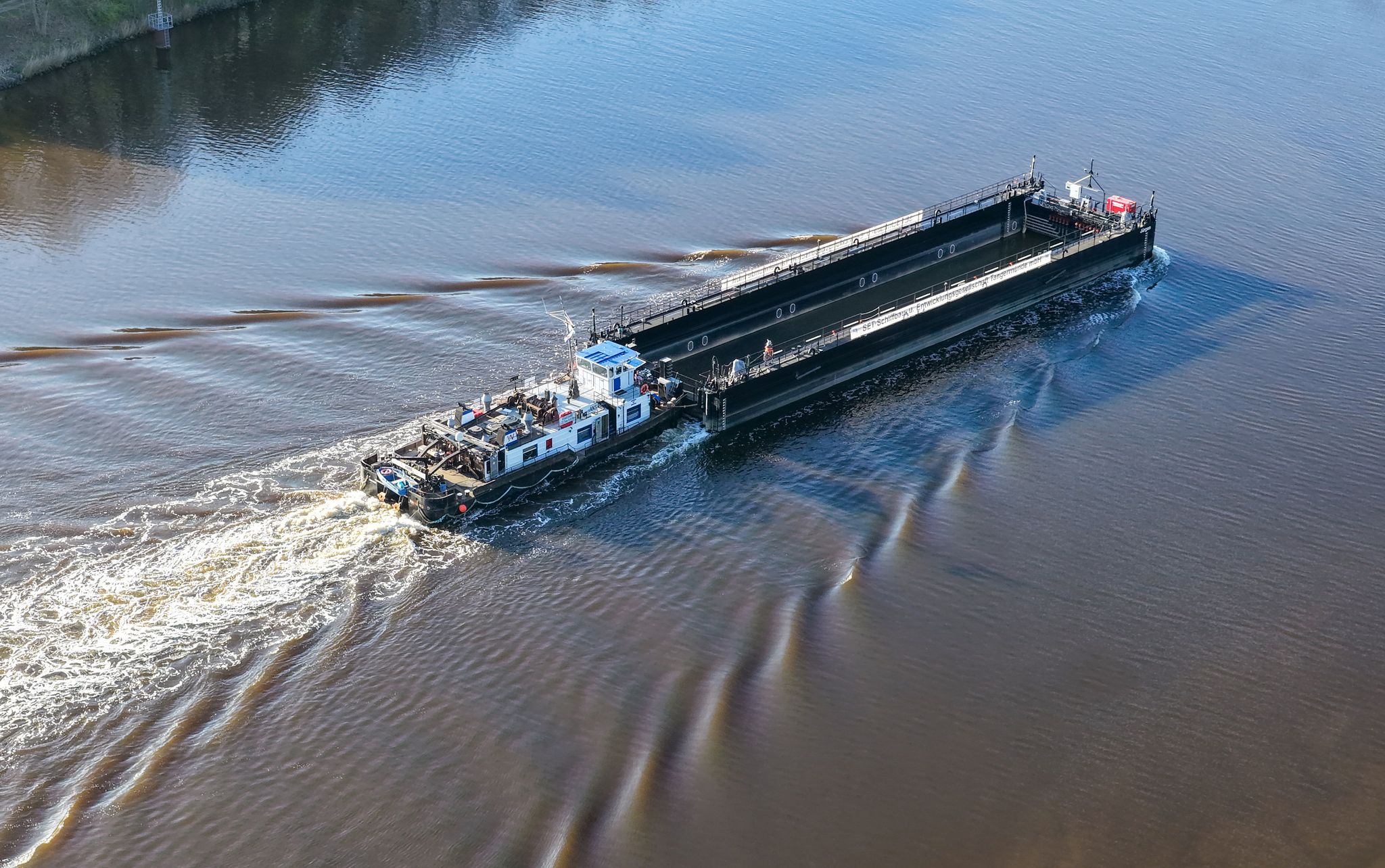 Ein Lastkahn, geschoben von dem Schubschiff «Hans» fährt auf dem Nord-Ostsee-Kanal. Foto: Bodo Marks/dpa
